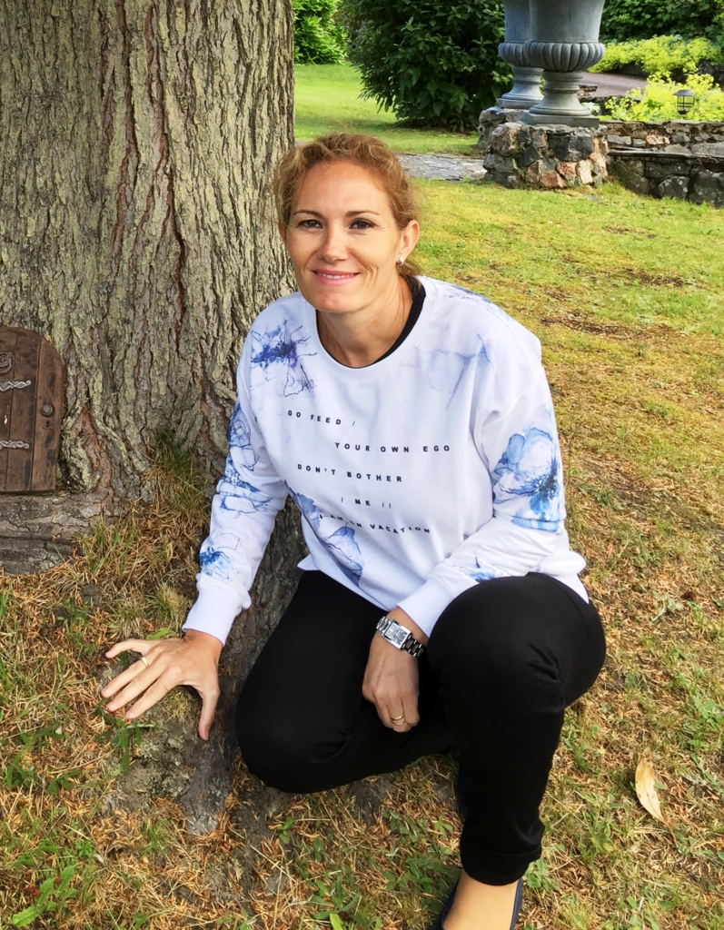 Maria del Carmen Álvarez Marin que está posando agachada junto a un árbol. Va vestida con ropa informal y está sonriente.